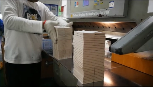 Worker aligning and stacking custom printed paper after cutting